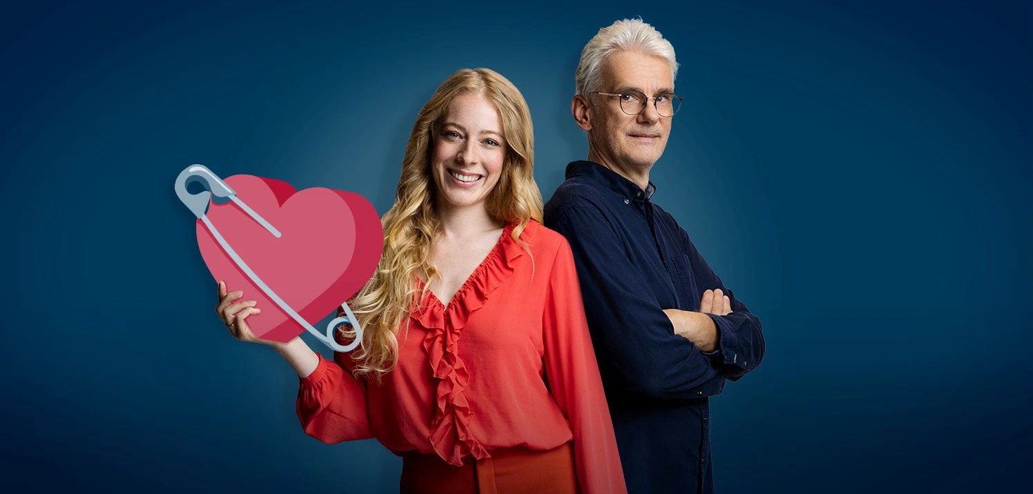 Anna Peinelt und Christian Thiel Rücken an Rücken vor tiefblauem Grund. Anna hält ein großes rotes Herz mit einer Sicherheitsnadel.